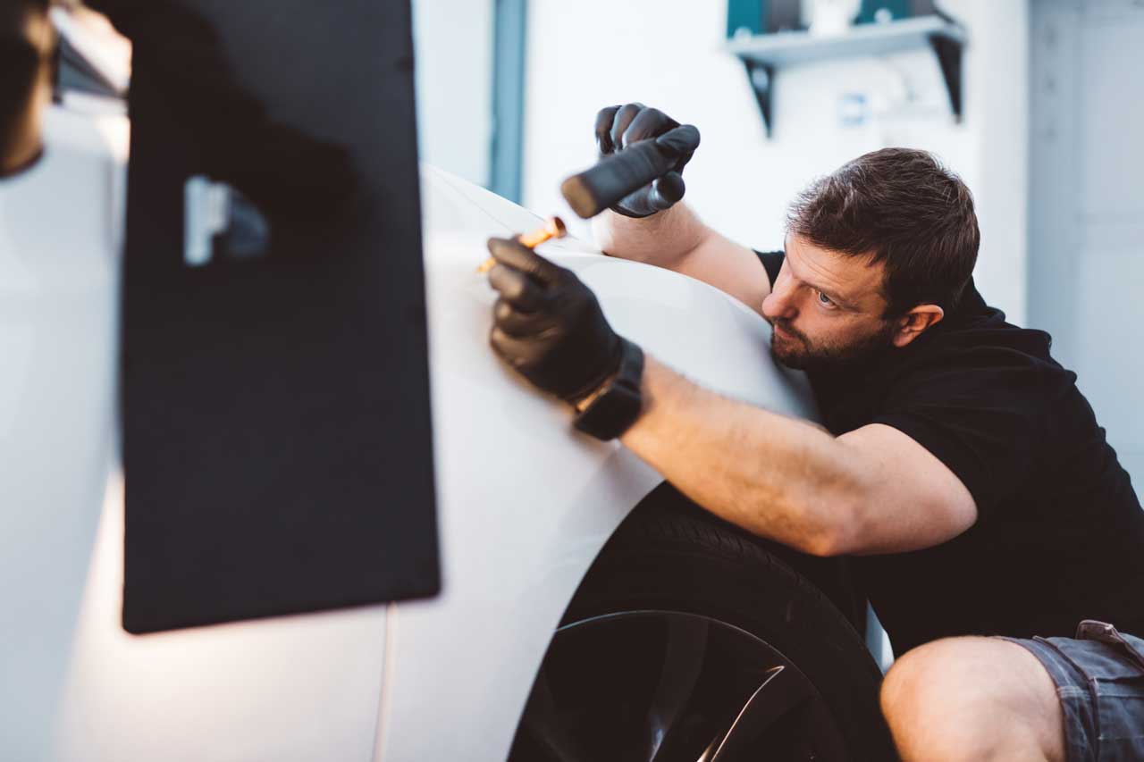 A skilled technician carefully repairs a dent in a car door